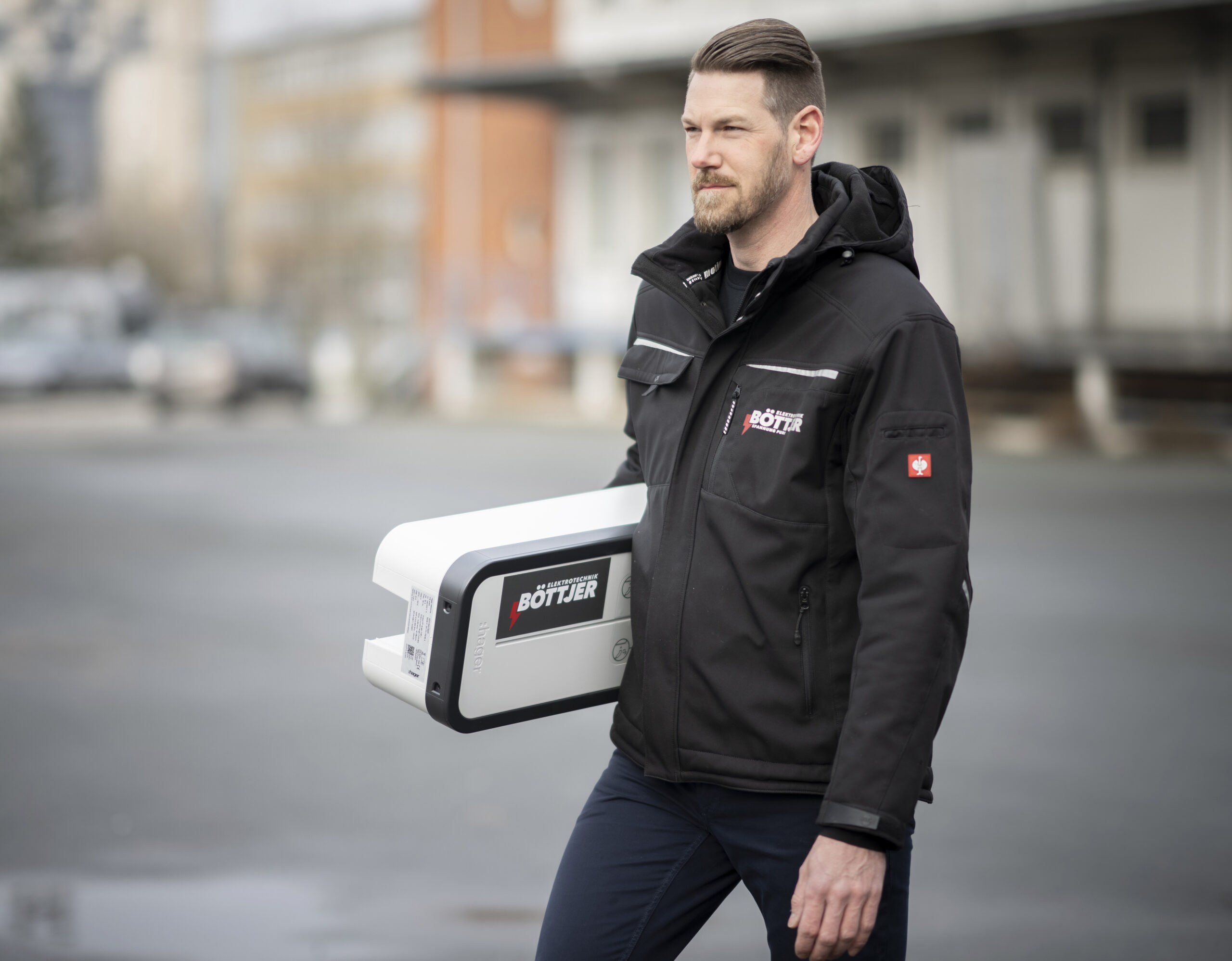 Ingo Böttjer trägt eine weiße Wallbox für das PV-Überschussladen