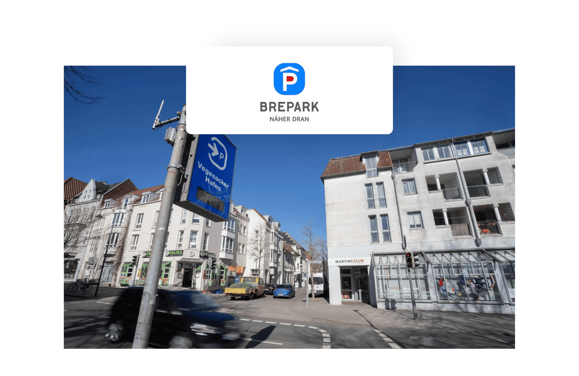 Straßenszene am Vegesacker Hafen in Bremen mit einem blauen Parkplatzschild der Brepark GmbH. Im Hintergrund sind Wohn- und Geschäftshäuser sowie der Eingang zum MARTINSCLUB zu sehen. Ein Auto fährt im Vordergrund vorbei. Der Himmel ist klar und blau.